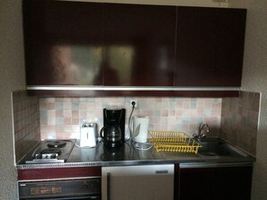 A compact kitchen with a stove, toaster, coffee maker, and a dishwasher.