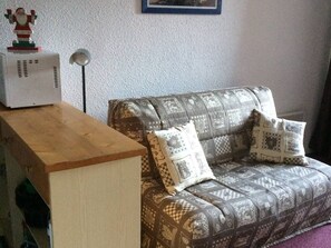Uma sala de estar com um sofá, uma mesa de madeira e um objeto decorativo sobre a mesa.