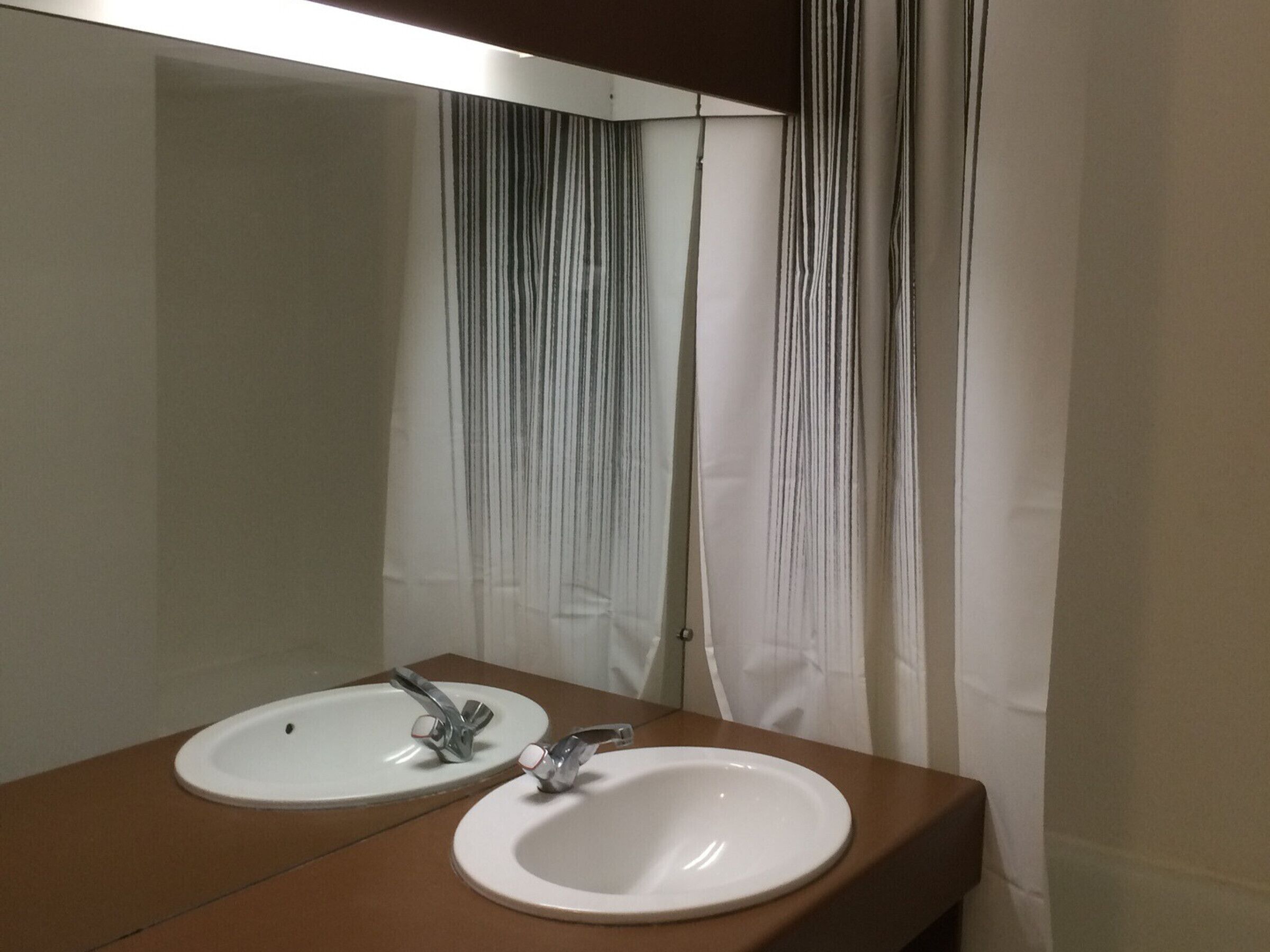 Une salle de bain avec deux lavabos, un miroir et un rideau de douche.