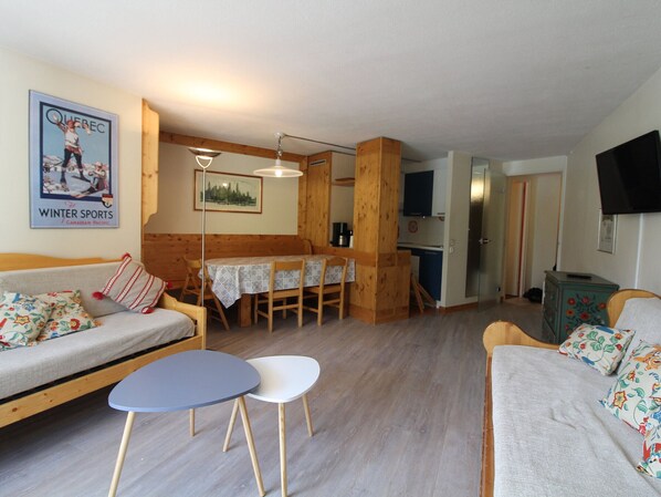 A cozy living room with a sofa, a small table, and a kitchen area in the background.