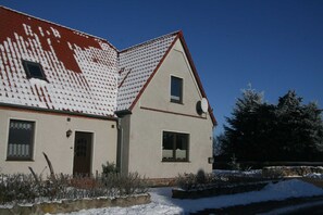 Ein zweistöckiges Haus mit rotem Ziegeldach, Steinmauerwerk und einer Satellitenschüssel.