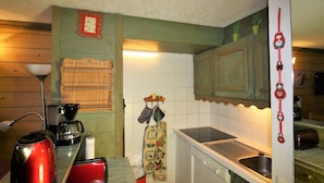 A compact kitchen with a red kettle, a coffee maker, and a dishwasher. - Classic studio for 4, south terrace lake view (Tignes)