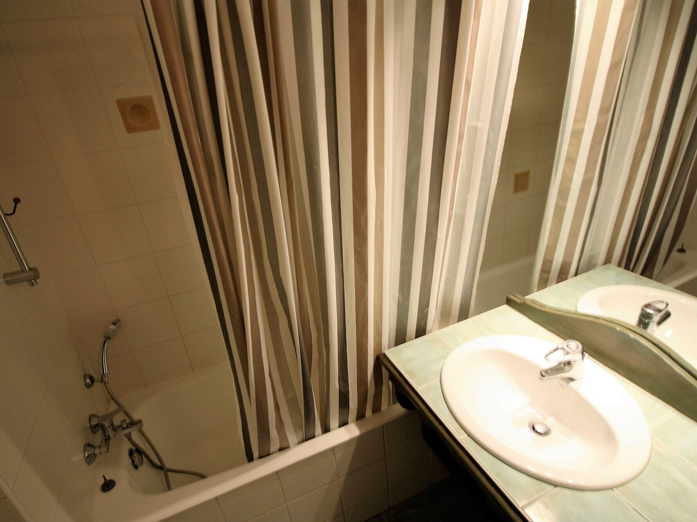 A bathroom with a shower, a sink, and a mirror.