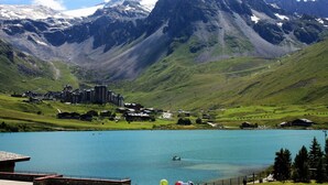 Paesaggio montuoso con un lago, edifici e cielo sereno.