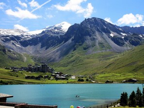 A mountainous landscape with a lake, buildings, and a clear sky.