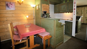 A cozy kitchen with wooden walls, a dining table with a red polka dot tablecloth, and a coffee maker. - Classic studio for 4, south terrace lake view (Tignes)