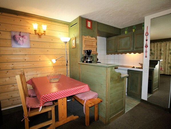 A cozy kitchen with wooden walls, a dining table with a red polka dot tablecloth, and a coffee maker.