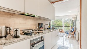 A modern kitchen with stainless steel appliances, a large window, and a view of the outdoors.