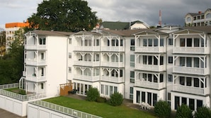 Un hotel a più piani con balconi, un prato e vista sugli edifici circostanti.