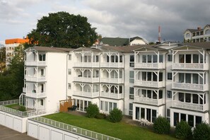 A multi-story hotel with balconies, a grassy lawn, and a view of surrounding buildings.