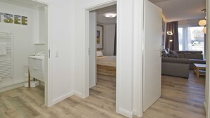 Una camera d'albergo moderna con pavimento in legno, un letto, un divano e un tavolino.