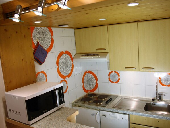 Una cucina con forno a microonde, fornello e lavello.