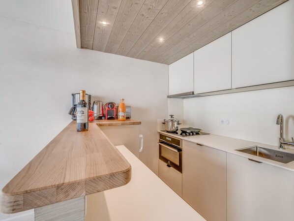 Una cocina moderna con encimeras de madera, electrodomésticos de acero inoxidable y horno empotrado.