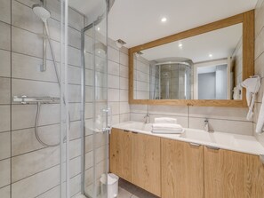 A modern bathroom with a glass-enclosed shower, a wooden vanity, and a large mirror.