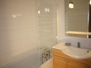 A bathroom with white tiles, a glass shower enclosure, a sink, and a mirror. - Renovated Apartment in Tignes - 6 Guests (Tignes-Le Lavachet)