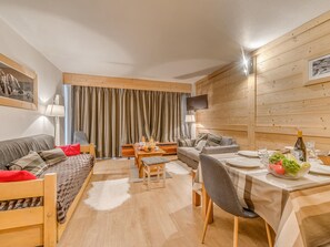 Uma sala de estar moderna com um sofá, mesa de jantar e TV fixada na parede.