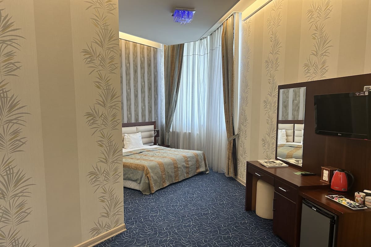 Ein Hotelzimmer mit Bett, Schreibtisch mit Fernseher und kleinem Kühlschrank.