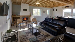 A cozy living room with a fireplace, leather sofa, and a dining area with a view.