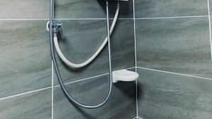 Ein Badezimmer mit einer an der Wand befestigten Duschkabine, einer Handbrause und einer Bedienkonsole.
