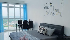 Ein modernes Schlafzimmer mit einem großen Bett, einem Schreibtisch und einem Stuhl. Durch das Fenster hat man Blick auf die Stadt.