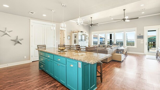A spacious kitchen with a central island, teal cabinetry, and pendant lighting.
