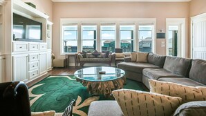 A spacious living room with a large window, a flat-screen TV, and a cozy seating area.