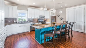 A spacious kitchen with white cabinets, a central island, and a dining area with wooden chairs.