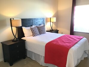A neatly made bed with a white and red bedspread, two bedside lamps, and a dark wooden headboard. - WOW! LOCATION! FUN! Includes HOT TUB, Gas Golf Cart, BBQ, & WIFI (The Villages)