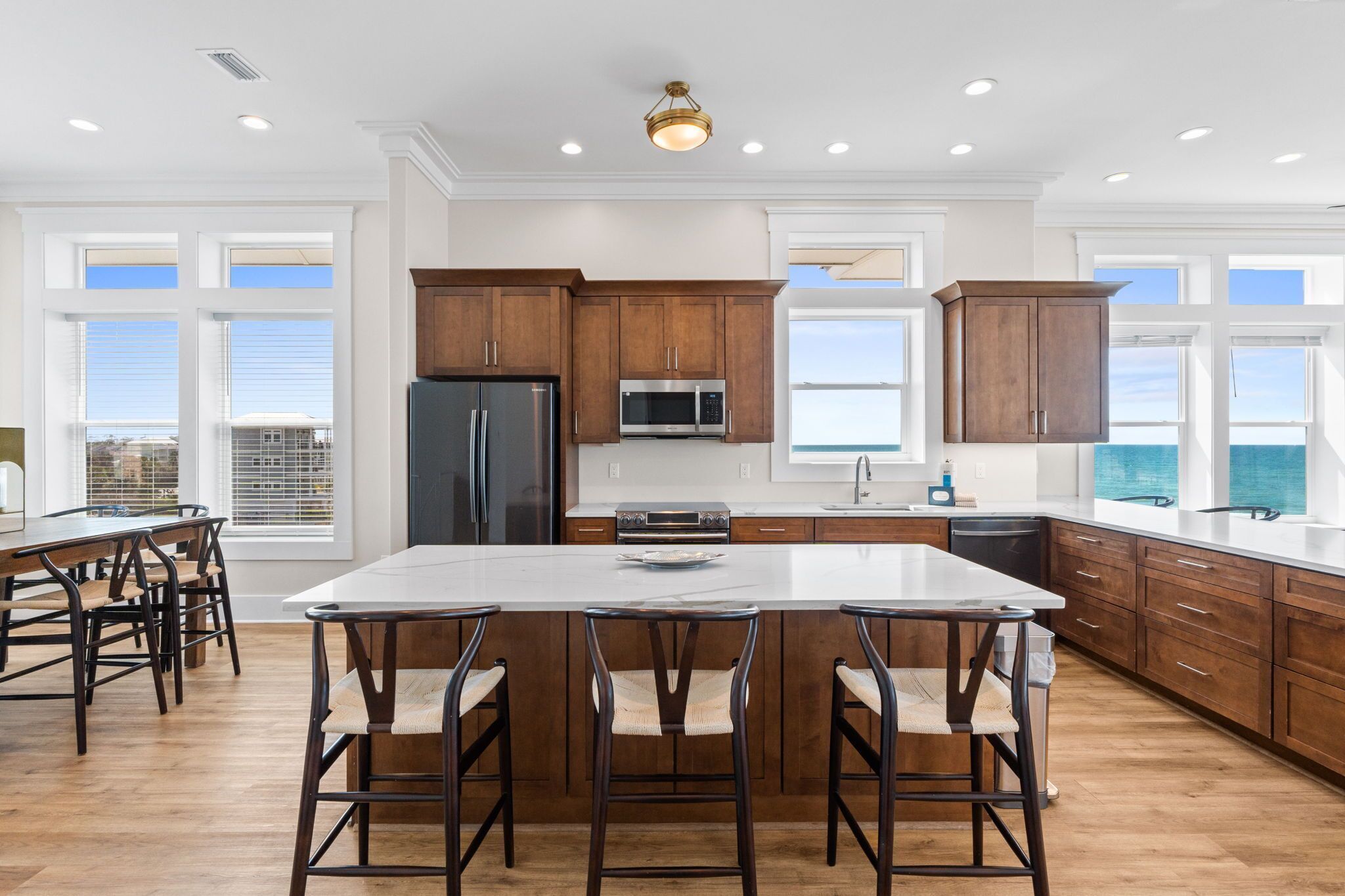 A spacious kitchen with a large island, wooden cabinets, stainless steel appliances, and large windows.