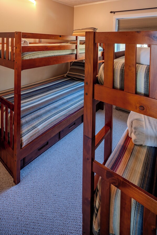 A room with bunk beds, carpeted floor, and a window with blinds. - Sugar Ski Comfort Unit 225 (Sugar Mountain)