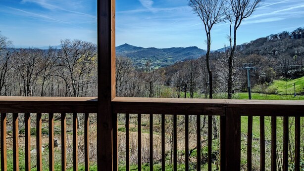 A wooden deck with a view of a mountainous landscape. - Sugar Ski Comfort Unit 225 (Sugar Mountain)