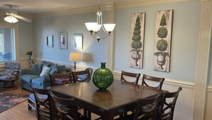 A dining room with a wooden table surrounded by chairs, a green vase, and a chandelier.