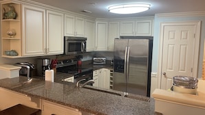 A modern kitchen with granite countertops, stainless steel appliances, and white cabinetry.