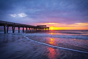 Une jetée qui s’avance dans l’océan au coucher du soleil, avec des vagues qui déferlent sur le rivage.