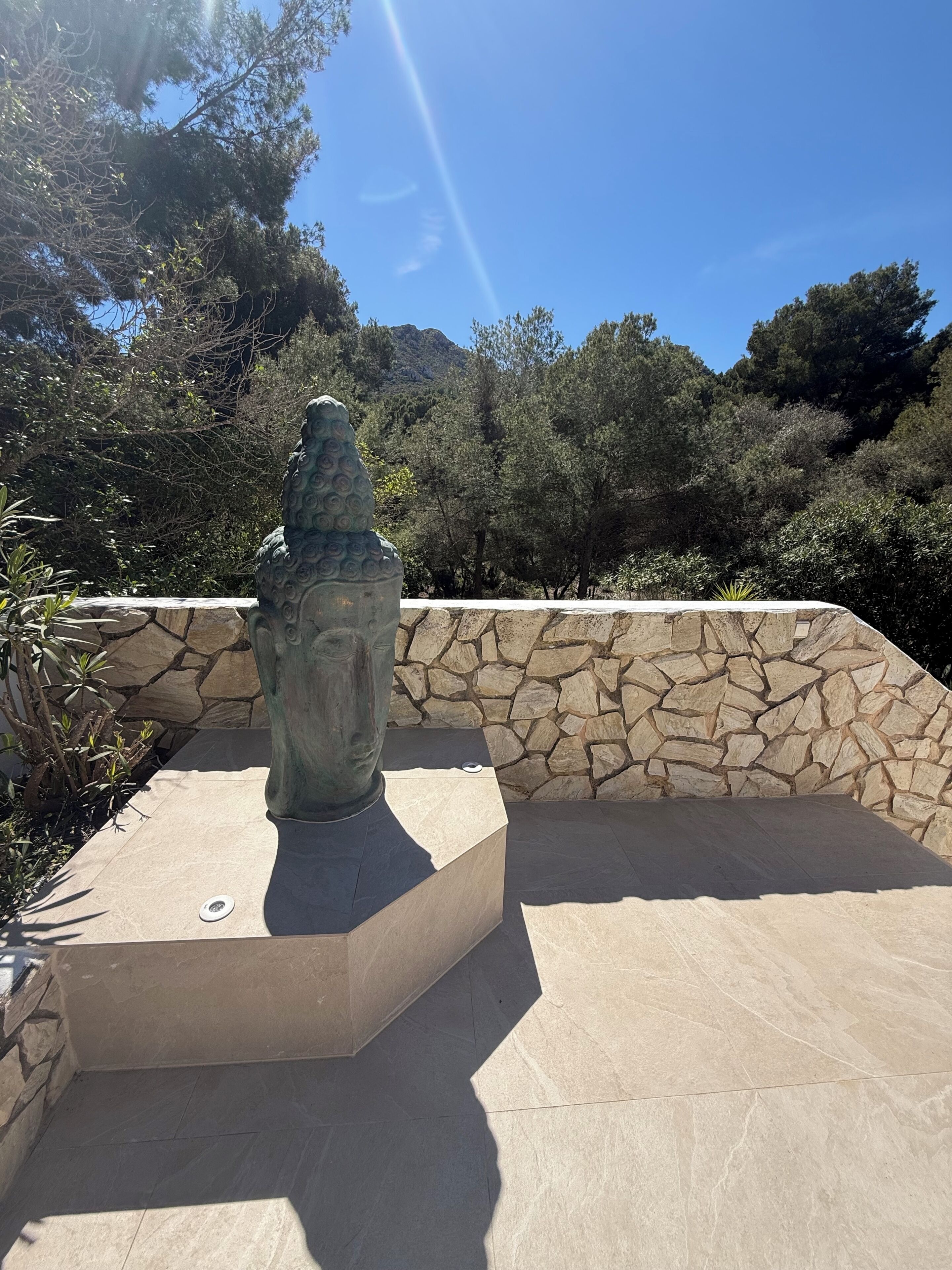 A stone wall with a statue on a platform.