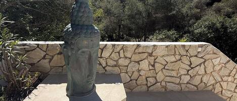 A stone wall with a statue on a platform.