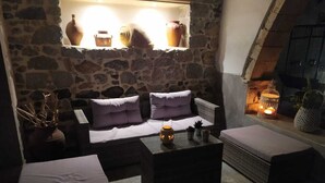 A cozy outdoor seating area with stone walls, a cushioned sofa, and a table with a lantern. - Romantic studio, city center, near beach, next market  and restaurants (Kalymnos)