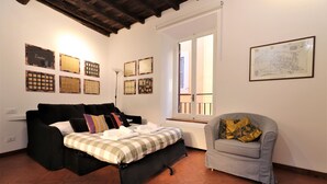 A bedroom with a bed, a sofa, a chair, and artwork on the walls.