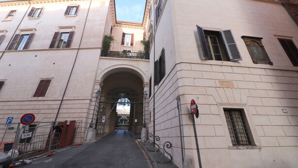 A narrow street with a large arched gateway between two buildings.