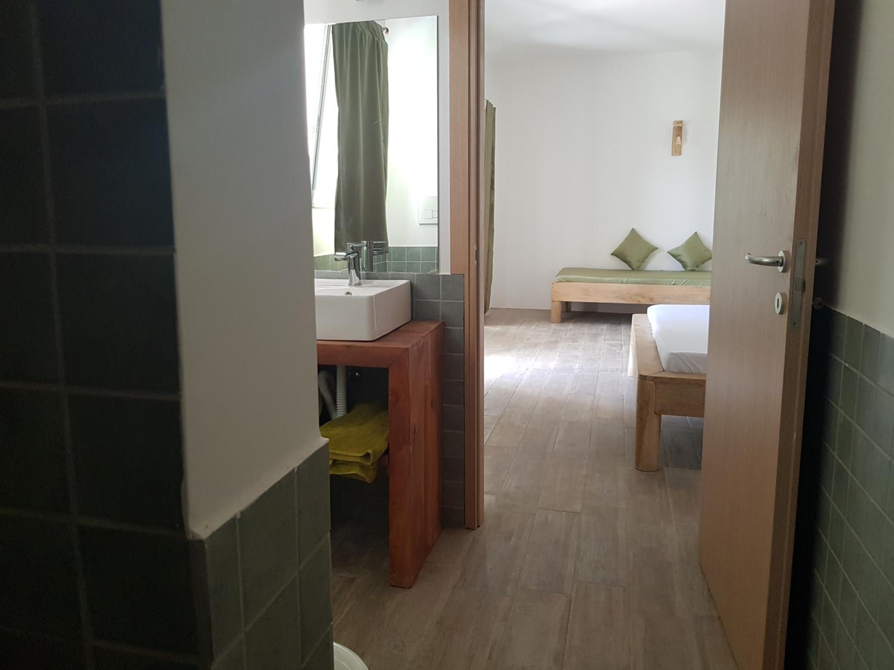 Et hotelværelse med badeværelse, seng og træbænk.