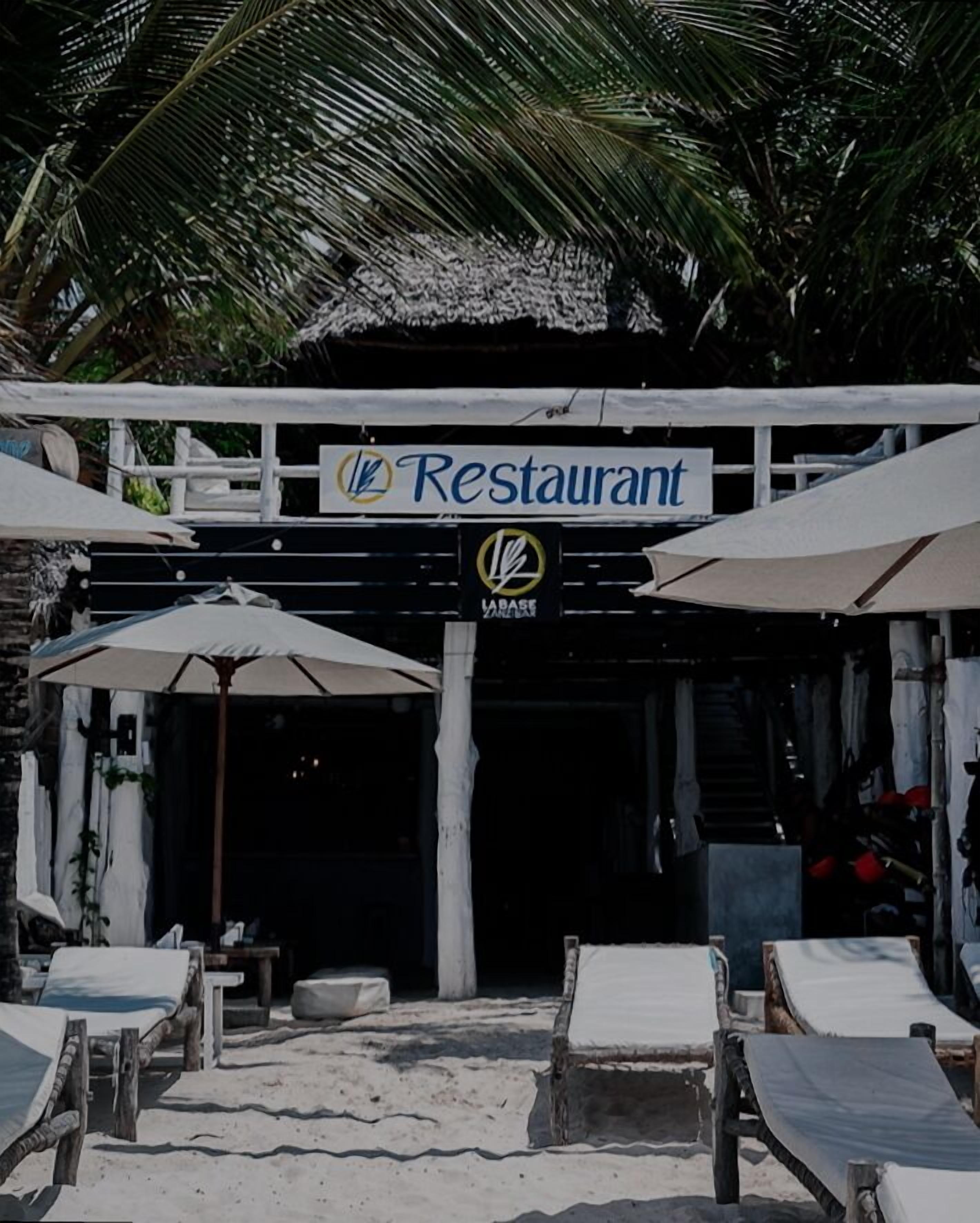 A beachside restaurant with outdoor seating and umbrellas.