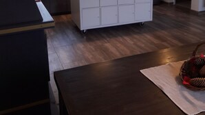 Eine moderne Küche mit einer zentralen Kochinsel, einem Kühlschrank und einer Pendelleuchte.