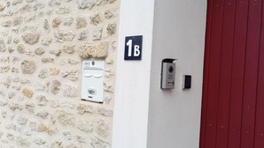 Eine Steinsäule mit einem 'Gîte'-Schild, einer Tür mit der Aufschrift '1B' und einem Gegensprechanlage.