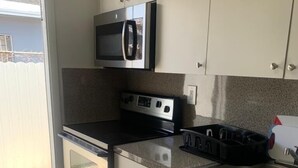Une cuisine moderne avec des armoires blanches, un évier en acier inoxydable, un four à micro-ondes et une cuisinière.