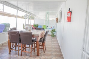 A covered patio with a wooden table and chairs, a fire extinguisher on the wall, and a view of the outside. - Private Duplex Near MIA & Port (Miami)