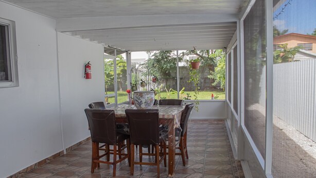 Une terrasse couverte avec une table et des chaises, un extincteur et des plantes en pot.