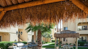 An outdoor patio area with a thatched roof, a grill station, and a gazebo. - Beautiful Las Vegas 2 Bdm Condo In Amazing Resort (Las Vegas)