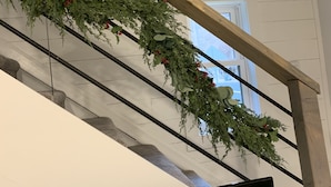 Una escalera con barandilla de madera y una guirnalda de follaje y bayas rojas.