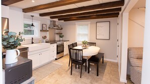 Una cocina moderna con armarios blancos, horno empotrado y comedor con mesa y sillas.
