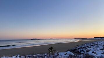 Une plage avec des rochers couverts de neige et un ciel dégagé.